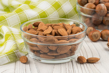 Almonds in a glass bowl on the old wooden table.