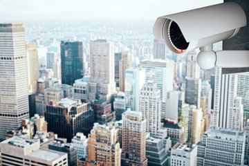 Fototapeta na wymiar Security camera on modern city background