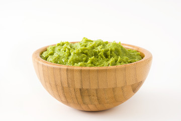 Guacamole in a wooden bowl isolated on white background
