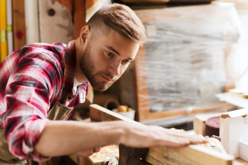 carpenter working with wood plank at workshop