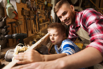 father and little son with wood plank at workshop