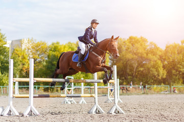 Young rider girl on horse show jumping competition