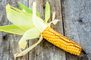 Single corn cob on rustic wooden background © alicja neumiler