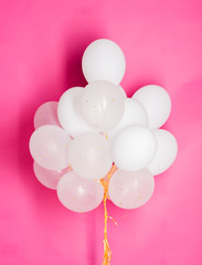close up of white helium balloons over pink