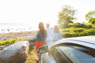 happy teenage girls or women near car at seaside