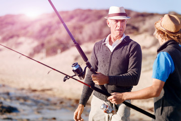 Obraz premium Senior man fishing with his grandson