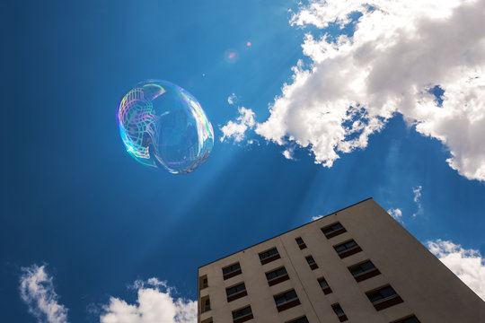Soap bubble in blue sunny sky, over city blocks. Freedom concept.