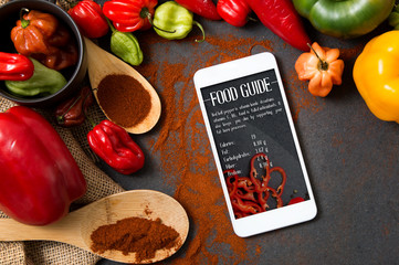 Smartphone with Food Guide application lying on stone counter and surrounded by different kinds of...