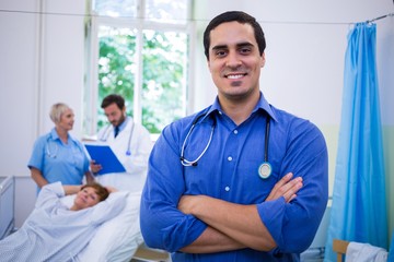 Smiling doctor standing with arms crossed in hospital