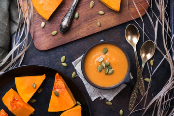 Pumpkin soup in a mug on grunge black table