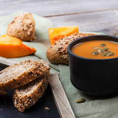 Pumpkin soup in a mug on rustic table