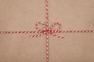 Christmas string or twine tied in a bow on kraft paper texture