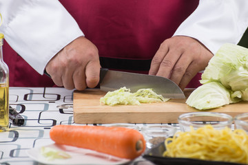 Chef sliing cabbage on wooden broad
