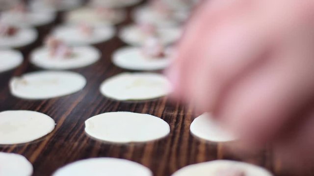 Close up of a preparing an eastern meal with dough in a kitchen. Putting meat in the middle of circle sliced dough. Meal called dushbara