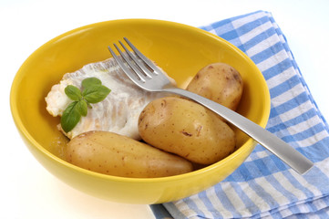 Assiette avec du dos de cabillaud, des pommes de terre et des feuilles de basilic