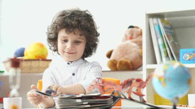 Child and book. Cute boy with black curly hair opens the book. Curly child. The boy opened a book of fairy tales. Delighted child. Boy with black curly hair look voluminous book with pictures.