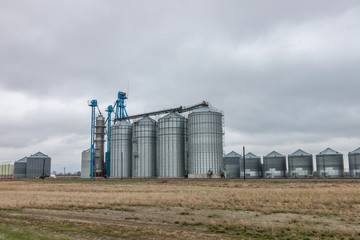 Fototapeta na wymiar Modern Grain Bins Against Cloudy Sky