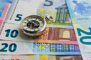 Time is money concept with euros and pocket watch.