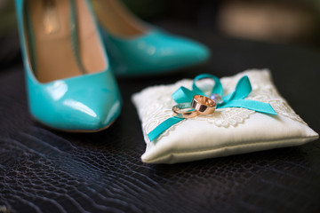 Obraz na płótnie Canvas Elegant wedding shoes composition. Turquoise color of shoes and wedding rings on a pillow.