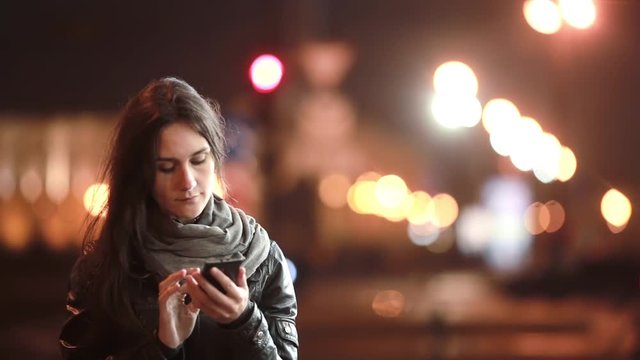 Pretty young woman makes a phone call. She talks on the phone in the street at cold night. Modern technology.