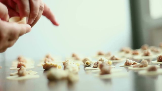 Close up of a preparing an eastern meal with dough in a kitchen. Wrap up circle sliced dough with meat. Meal called dushbara