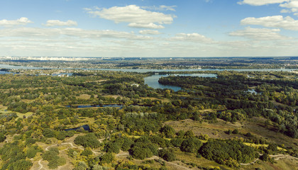 Fototapeta premium Panoramic view of the Kiev suburb from above. Aerial view. Outdoor. Beautiful photos of nature with fields river and reservoirs with high-rise buildings in the background.