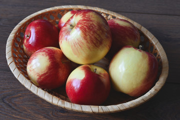 Red apples autumn harvest in a small wicker basket