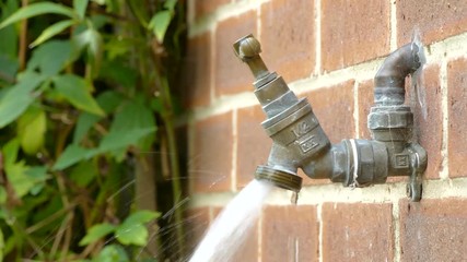 Slowly panning around an outside running tap in summer