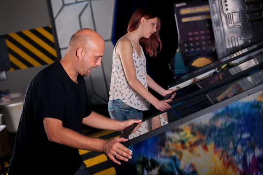 Young woman playing on the pinball machine