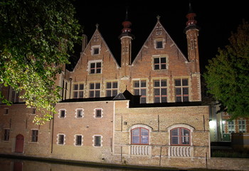 Naklejka premium Embankment at night in Bruges, Belgium. View on medieval house 