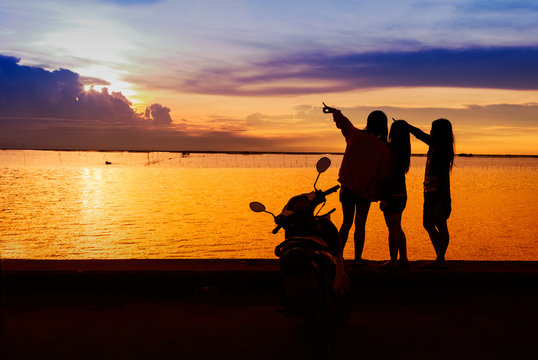 Group of happy young girls standind on the beach at sunset time