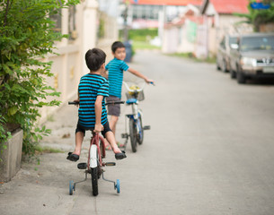 Fototapeta na wymiar Little boy riding bicycle on the road around the house