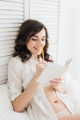 Girl writes in a notebook in bed