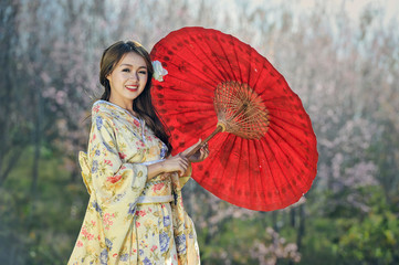 Attractive asian woman wearing traditional Japanese Kimono with red umbrella