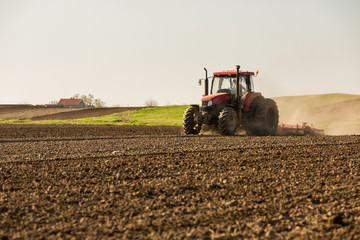 Farmer in tractor preparing land with seedbed cultivator