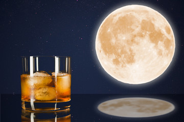 Whiskey glass on midnight sky with full moon background.
