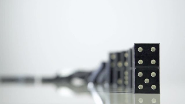 Row of dominoes with one falling over