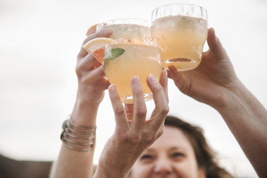 Three women standing in a desert landscape toasting each other.  Raising glasses. 