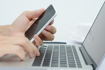 man using mobile phone and laptop