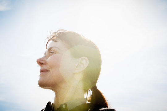 A woman, low angle view, side profile, looking upwards. Lens flare.