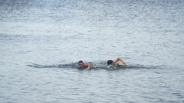 Two guys competing in speed swim in the lake. Slow motion . High speed camera