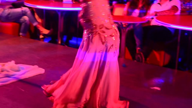 Girl dancing Eastern harem oriental dance in a nightclub. Focus on a lower portion of the torso.