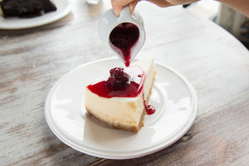 pouring blueberry sauce topping on cheese cake.