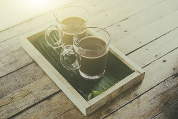 Old traditional Thai style coffee and hot chocolate or cocoa on the wooden table, sunshine and flare light blurred background, soft focus