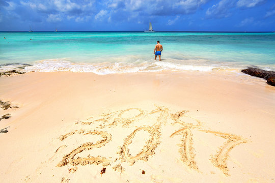 Happy New Year 2017 replace 2016 concept on the sea beach. Numbers 2017 and 2016 handwritten on seashore sand. New year 2017. Celebration of the new year on the tropical coast.