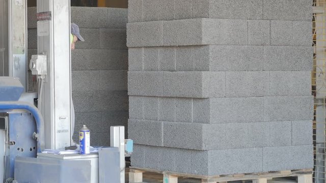 Operator works on the strapping machine at the concrete blocks factory