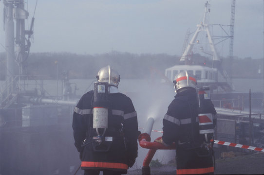  Firefighter extinguishing a fire on a ship (Pompiers éteignant un feu sur un navire), France, Europe.