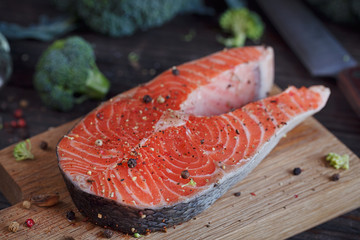 Raw salmon steak with sea salt, pepper and broccoli