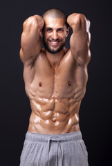 Smiling fit man flexing the abdominal on black background