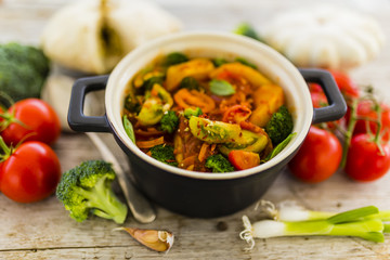 Pattison stewed with vegetables in tomato sauce on a wooden table. Vegetarian food.